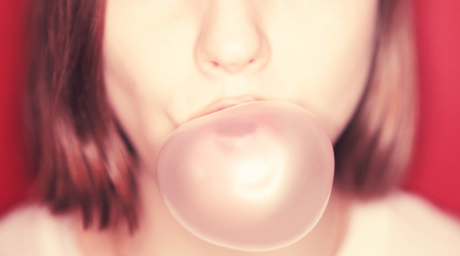 Woman with red hair blows a large pink gum bubble