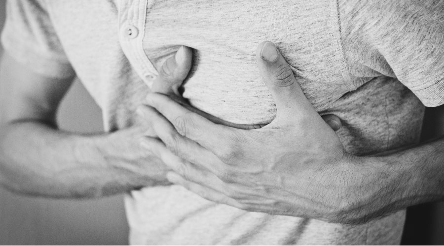 man holding his chest with acid reflux and heartburn