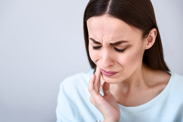 woman holding her mouth in pain