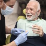 senior man receiving his dentures at the dentist with tips on oral health with dentures and implants