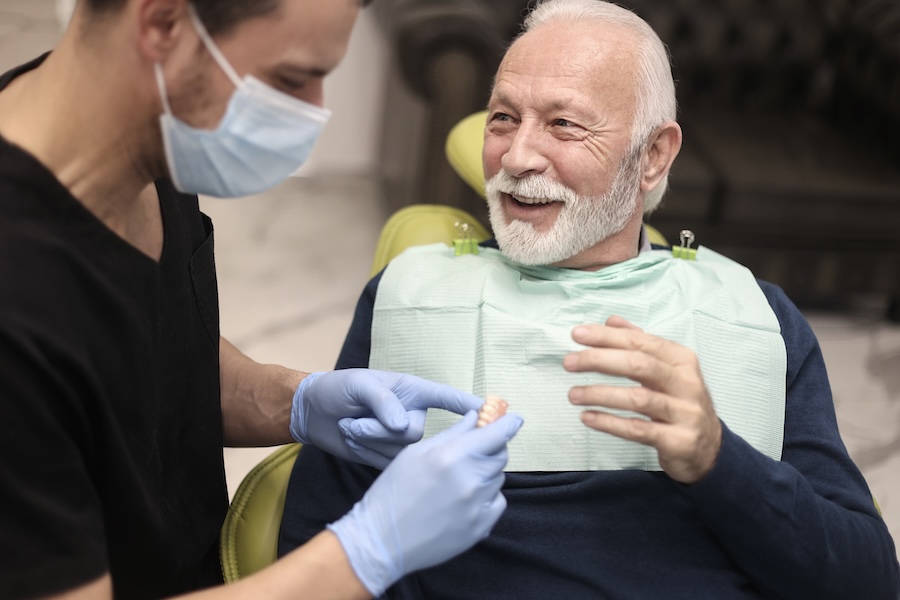 senior man receiving his dentures at the dentist with tips on oral health with dentures and implants